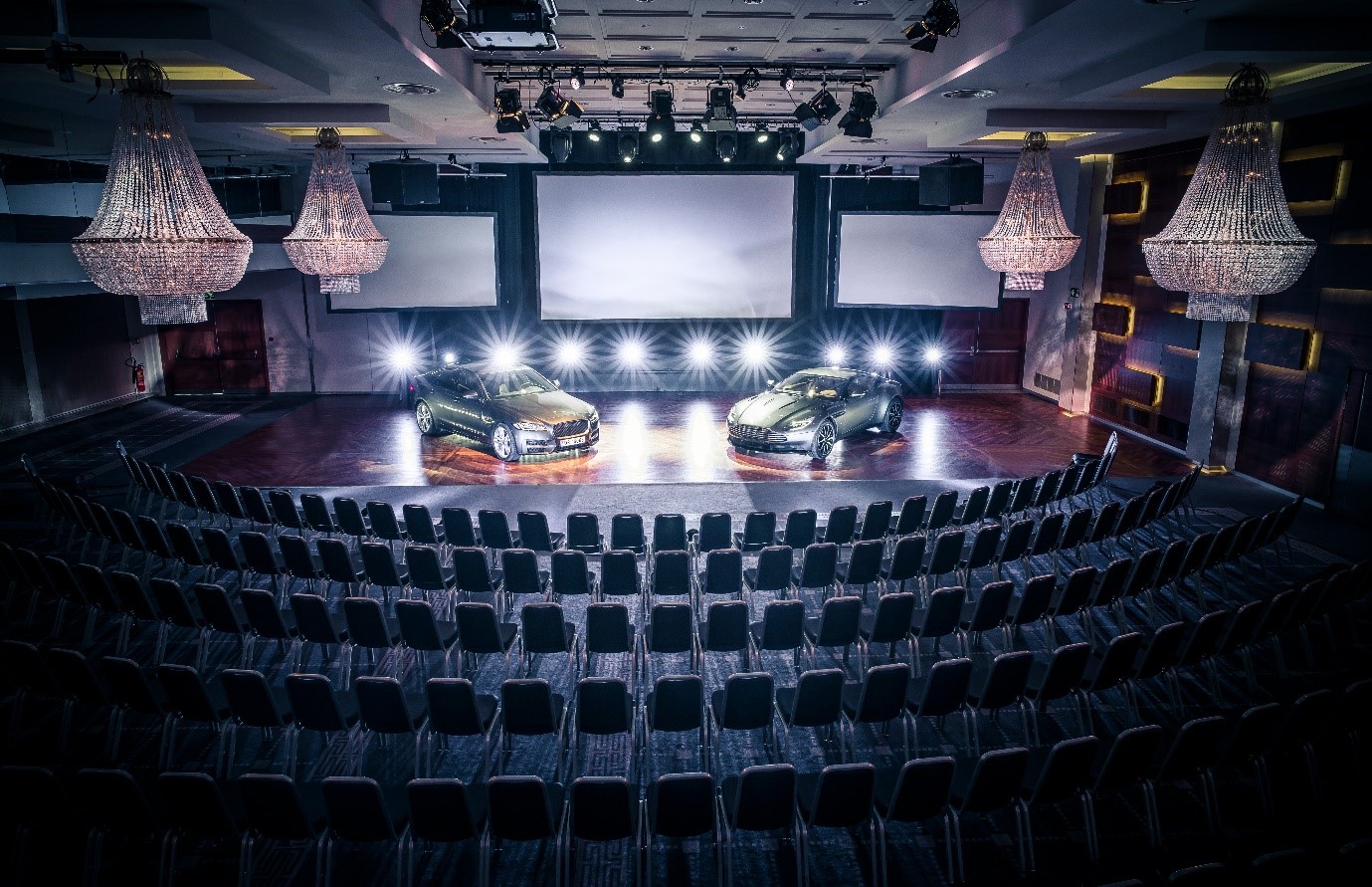 A car on a stage with chairs and a screen
